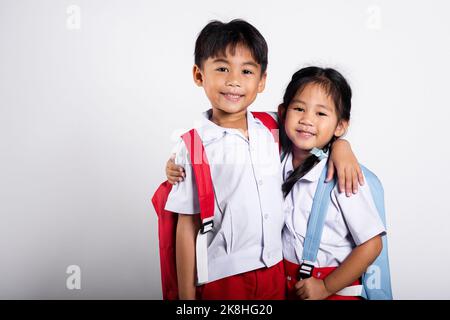 Zwei asiatische Student Kind Mädchen junge Schulkinder Bruder Schwester lächeln glücklich tragen Student thai uniform rote Hosen Rock umarmen einander isoliert auf weißen BA Stockfoto