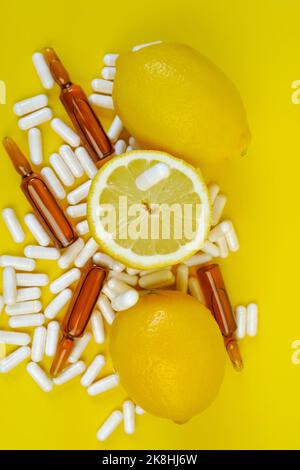 Vitamin-C-Tabletten auf gelbem Hintergrund. Viele Pillen und Zitrusfrüchte. Fliegende Vitamin-C-Pillen und Zitronen geschnitten. Natürliche Früchte Vitamin C.Immunität Stockfoto