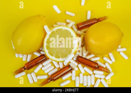 Vitamin-C-Tabletten auf gelbem Hintergrund. Pillen und Zitrusfrüchte. Fliegende Vitamin C Pillen und Zitronen geschnitten. Natürliche Frucht Vitamin C.. Stockfoto