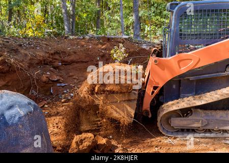 Kleiner Traktor, der zur Bodenbewegung für die Landschaftsgestaltung auf der Baustelle verwendet wurde. Stockfoto