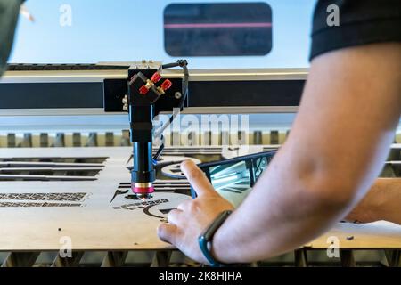 Laserschneidemaschine, Schneiden von Holzplatten, während ein Mann zeichnet den Prozess, mexiko Stockfoto