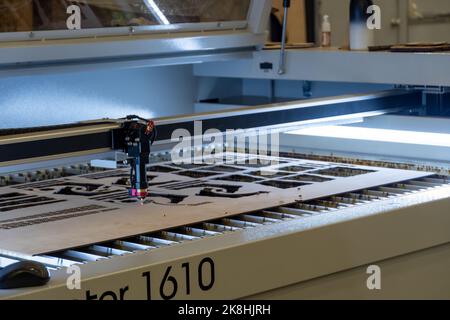 Laserschneidemaschine, Schneiden von Holzplatten, während ein Mann zeichnet den Prozess, mexiko Stockfoto