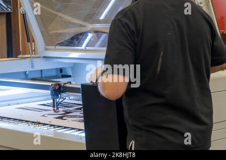 Laserschneidemaschine, Schneiden von Holzplatten, während ein Mann kümmert sich um den Prozess, lateinamerika Stockfoto