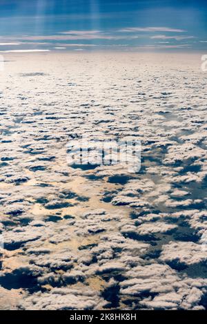 Eine Schicht aus verstreuten Cumuluswolken von oben, mit dem warmen Sonnenlicht am späten Nachmittag, das sich im Südchinesischen Meer widerspiegelt Stockfoto