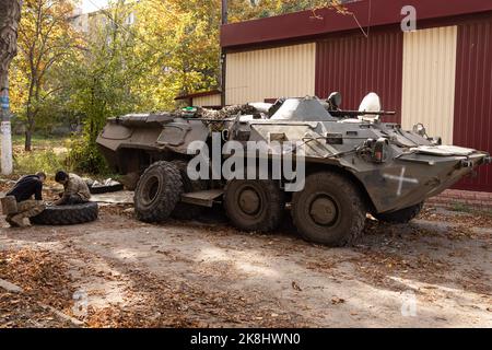 Ukrainische Soldaten wechseln die Reifen auf einem APC, einem gepanzerten persönlichen Träger der ukrainischen Armee in der Nähe eines beschädigten Gebäudes nach einem russischen Beschuss in der Stadt Bakhmut. Bakhmut ist eine der am schlimmsten beschossen Städte an den Fronten des Donbass-Krieges, seit Russland am 24. Februar 2022 seine umfassende Invasion in der Ukraine startete. Stockfoto