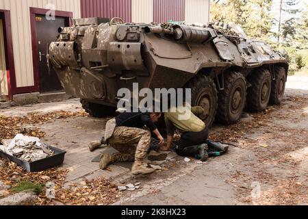 Bakhmut, Ukraine. 19. Oktober 2022. Ukrainische Soldaten wechseln die Reifen auf einem APC, einem gepanzerten persönlichen Träger der ukrainischen Armee in der Nähe eines beschädigten Gebäudes nach einem russischen Beschuss in der Stadt Bakhmut. Bakhmut ist eine der am schlimmsten beschossen Städte an den Fronten des Donbass-Krieges, seit Russland am 24. Februar 2022 seine umfassende Invasion in der Ukraine startete. (Foto von Jan Husar/SOPA Images/Sipa USA) Quelle: SIPA USA/Alamy Live News Stockfoto