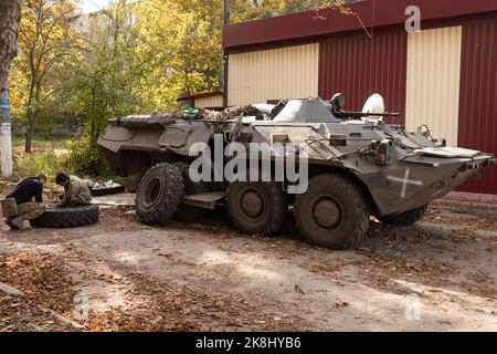 Bakhmut, Ukraine. 19. Oktober 2022. Ukrainische Soldaten wechseln die Reifen auf einem APC, einem gepanzerten persönlichen Träger der ukrainischen Armee in der Nähe eines beschädigten Gebäudes nach einem russischen Beschuss in der Stadt Bakhmut. Bakhmut ist eine der am schlimmsten beschossen Städte an den Fronten des Donbass-Krieges, seit Russland am 24. Februar 2022 seine umfassende Invasion in der Ukraine startete. (Bild: © Jan Husar/SOPA Images via ZUMA Press Wire) Stockfoto