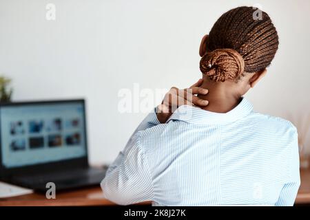 Die Schmerzen und Strapazen eines langen Tages. Eine Geschäftsfrau, die Nackenschmerzen bei der Arbeit erlebt. Stockfoto
