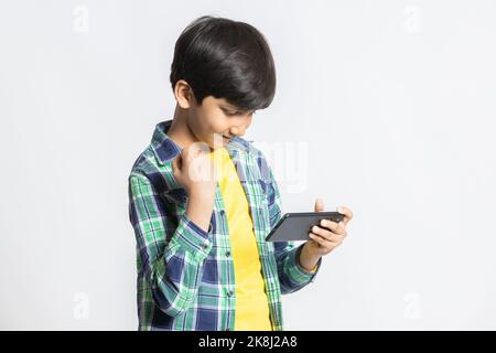 Freizeit, Kinder, Technologie, Internet-Kommunikation und Menschen-Konzept- netter kleiner indischer Junge spielt Spiel über Smartphone, asiatisches Kind gewinnt gestu Stockfoto