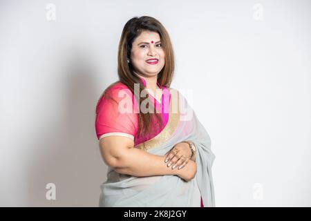 Porträt einer glücklichen, selbstbewussten indischen Frau in der Stadt, die Sari auf weißem Hintergrund trägt. Lächelndes asiatisches Weibchen in traditionellem Outfit, das sich ansah, kam Stockfoto