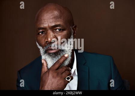 Ich bin bereit, alles zu tun, was es an diesem Punkt braucht. Studioaufnahme eines reifen Geschäftsmannes, der vor braunem Hintergrund posiert. Stockfoto