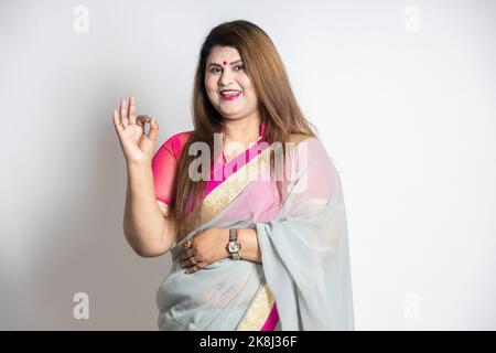 Glückliche indische Frau trägt Saree Hand mit ehrfürchtigen oder guten Ausdruck isoliert auf weißem Hintergrund. Übergewichtige oder dicke Dame lächelt. Null-Prozent-Inter Stockfoto