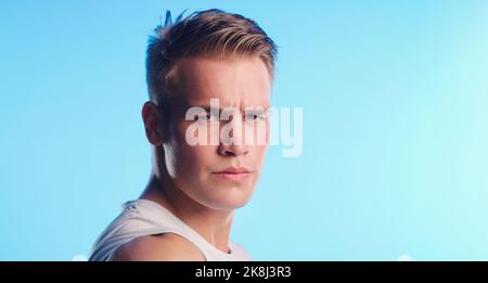 Voll auf Fitness ausgerichtet. Studioporträt eines hübschen jungen Mannes, der vor blauem Hintergrund posiert. Stockfoto