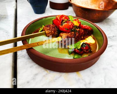 Kebabs auf Spieße. Hühnchen-Kebabs in einer grünen und braunen Schüssel in einem schicken Restaurant. Stockfoto