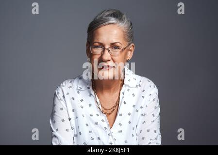 Wir alle haben uns gegenseitig etwas beizubringen. Studioaufnahme einer älteren Frau, die vor einem grauen Hintergrund posiert. Stockfoto