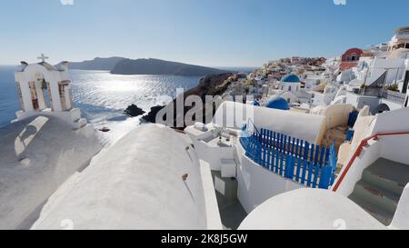 Blick auf die Stadt Oia und Caldera vom Kirchendach mit Kirchenglocken im Vordergrund. Griechische Kykladen-Insel Santorin in der Ägäis. Stockfoto