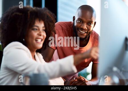 Dazu brauche ich Ihre Hilfe. Zwei junge Designer, die sich etwas auf einem Computerbildschirm anguchten. Stockfoto