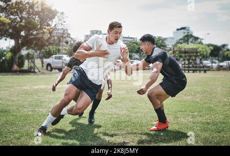 Laufen Sie zu den Pfosten. Ein fokussierter junger Rugby-Spieler im Wettbewerb gegen seine Gegner während eines Spiels außerhalb auf einem Filed. Stockfoto