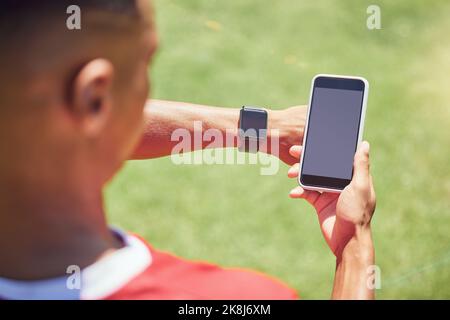 Grüner Bildschirm, Fußballspieler und Telefon auf dem Spielfeld mit Smartwatch, Tech oder Mockup auf der mobilen digitalen App. Mann, Fußballspieler oder Smartphone auf Social Media Stockfoto