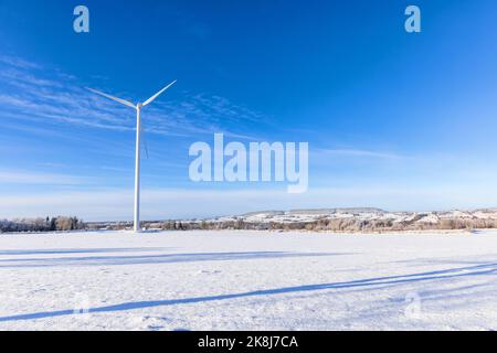 Windturbine in einem verschneiten Feld mit Blick auf die Landschaft Stockfoto