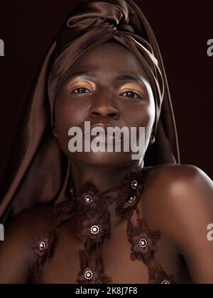 Packen Sie sich ein wie das Geschenk, das Sie sind. Studioporträt einer attraktiven jungen Frau, die in traditioneller afrikanischer Kleidung vor schwarzem Hintergrund posiert. Stockfoto