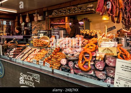 Kiosk mit verschiedenen geräucherten und geräucherten Fleischsorten sowie traditionellen Backwaren während des berühmten Weihnachtsmarktes in Wien, Österreich. Stockfoto