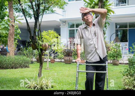 Glücklicher alter älterer asiatischer Mann benutzt einen Spaziergänger und spaziert im Hinterhof. Konzept der glücklichen Ruhestand mit der Betreuung von einem Betreuer und Sparer und Senior er Stockfoto