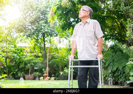 Glücklicher alter älterer asiatischer Mann benutzt einen Spaziergänger und spaziert im Hinterhof. Konzept der glücklichen Ruhestand mit der Betreuung von einem Betreuer und Sparer und Senior er Stockfoto