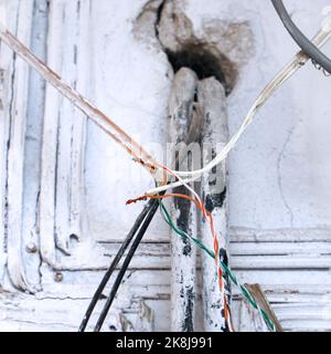 Gefahr durch elektrische Verdrahtung. Freiliegender Draht in der elektrischen Verkabelung in der Wand. Selektiver Fokus Stockfoto