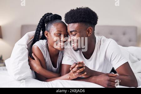 Ich habe mich nie mehr wie zu Hause gefühlt. Ein liebevolles Paar, das sich im Schlafanzug auf dem Bett entspannt. Stockfoto