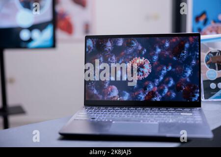 Nahaufnahme des Computerbildschirms mit mikroskopischen Bildern von Viren. Proben von bösartigen Mikroorganismenzellen auf dem Laptop-Monitor in der medizinischen Einrichtung gesehen. Tragbarer pc auf dem Schreibtisch mit Bildern des Coronavirus. Stockfoto