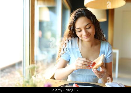 Vorderansicht einer glücklichen Frau, die in einem Restaurant Tomaten auf Brot streut Stockfoto