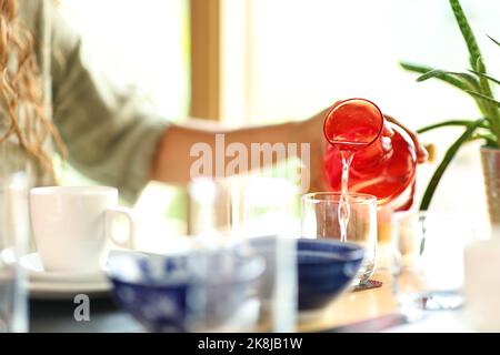 Nahaufnahme eines Porträts einer Frau, die in einem Restaurant Glas mit Wasser aus der Flasche füllte Stockfoto