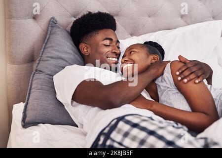 Ich fand meinen glücklichen Platz in seinen Armen. Ein liebevolles Paar, das sich im Schlafanzug auf ihrem Bett erholte. Stockfoto