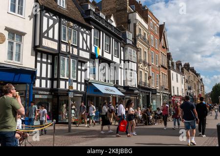 Ein Blick entlang der Kings Parade, Cambridge, Großbritannien, mit vielen Touristen, die an den Geschäften und Cafés vorbeikommen. Stockfoto