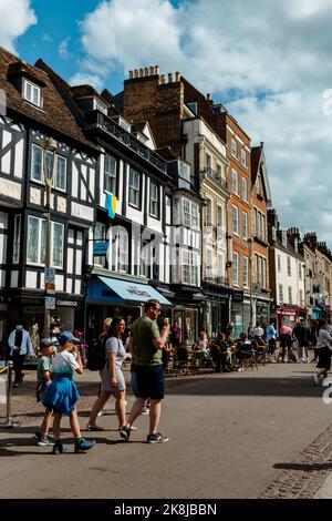 Ein Blick entlang der Kings Parade, Cambridge, Großbritannien, mit vielen Touristen, die an den Geschäften und Cafés vorbeikommen. Stockfoto