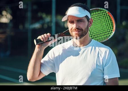 Ich lasse meinen Schläger reden. Porträt eines sportlichen jungen Mannes, der mit einem Tennisschläger auf einem Tennisplatz steht. Stockfoto