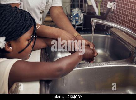 Ich unterrichte sie über die Bedeutung guter Hygiene. Eine Mutter und Tochter waschen sich im Spülbecken die Hände. Stockfoto