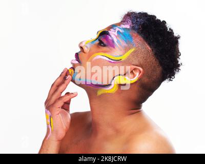 Lebe das Leben nach deinen eigenen Regeln. Ein junger Mann mit fließenden Geschlechtern, der Gesichtsfarbe auf weißem Hintergrund trägt. Stockfoto