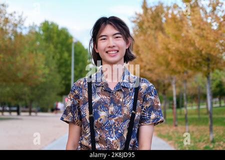 Porträt eines Taiwanesen, der lächelt und in einem Park auf die Kamera schaut. Stockfoto