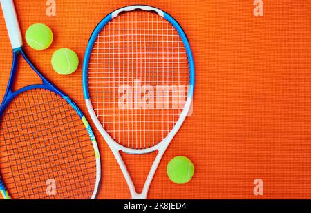 Du hast dein Spiel getroffen. High-Angle-Aufnahme von Tennis Essentials auf einem orangefarbenen Hintergrund im Studio. Stockfoto