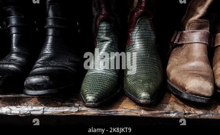 Abgenutzte Cowboy-Schuhe. Alte Stiefel im Regal Stockfoto