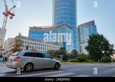 Hochhaus-Kran baut Wolkenkratzer im Verwaltungszentrum von Warschau. Stadtverkehr in Warschau. Geschäftsbüros im zentralen Stadtbezirk der Innenstadt mit Autoverkehr Stockfoto