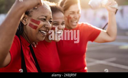 Fußballfans jubelten beim Fußballspiel im Stadion - Frauen mit gemaltem Gesicht und Megaphon ermutigen ihr Team Stockfoto