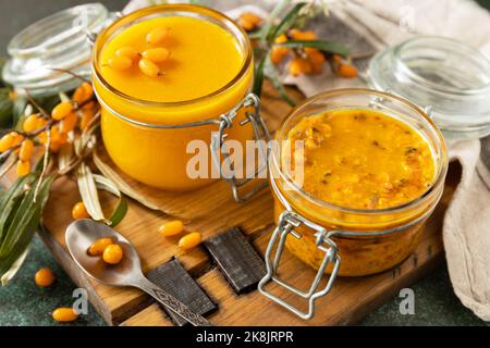 Hausgemachte, konservierte Beeren. Frische reife Sanddornbeere mit Zucker und Sanddorngelee auf einem Steintisch. Stockfoto