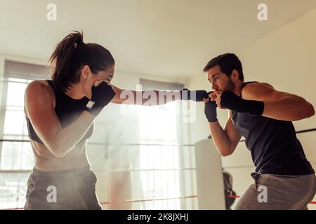 Junge Boxer kämpfen in einem Boxring. Zwei junge Kämpfer stehen sich während eines Trainings in einer Boxhalle gegenüber. Stockfoto