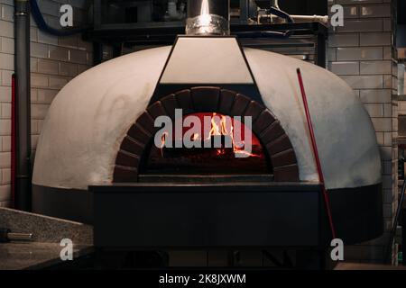 Traditioneller Kaminofen mit brennendem Feuer, bereit für traditionelle italienische Pizza, Brot oder Bäckereien Stockfoto