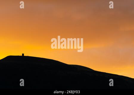 Orangefarbene Wolken bei Sonnenaufgang im Herbst fallen über Rivington Pike Winter Hill Lancashire England mit Kopierraum Stockfoto