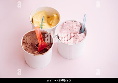 Set von Schalen mit verschiedenen bunten Eis mit verschiedenen Geschmacksrichtungen und frischen Zutaten auf rosa Hintergrund, Draufsicht Stockfoto