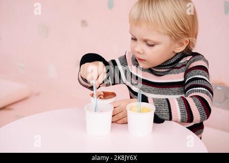 Kinder essen Eis in einem Café. Set von Schüsseln mit verschiedenen Eiscreme mit verschiedenen Geschmacksrichtungen und frischen Zutaten Stockfoto
